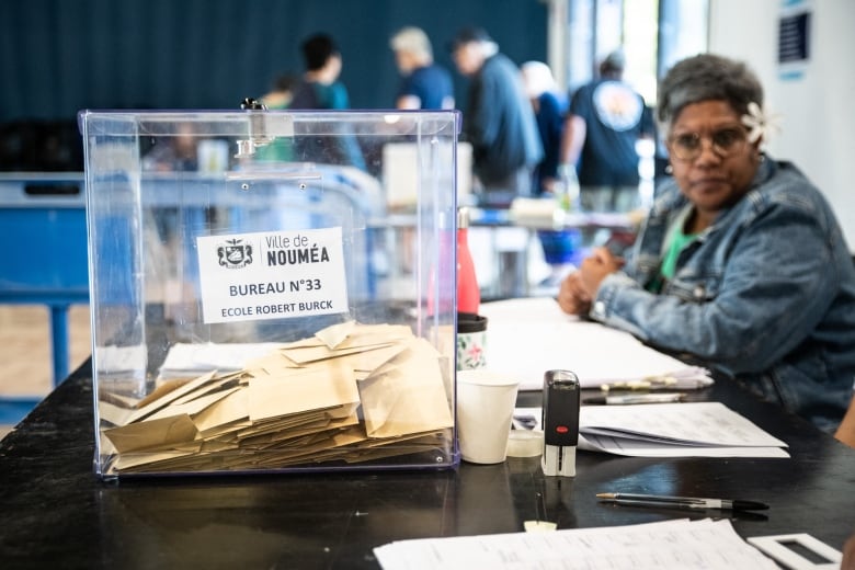 A clear box filled with envelopes is pictured on a table.