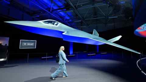 A person walks past the Global Combat Air Programme fighter jet concept design on the opening day of the Farnborough International Airshow