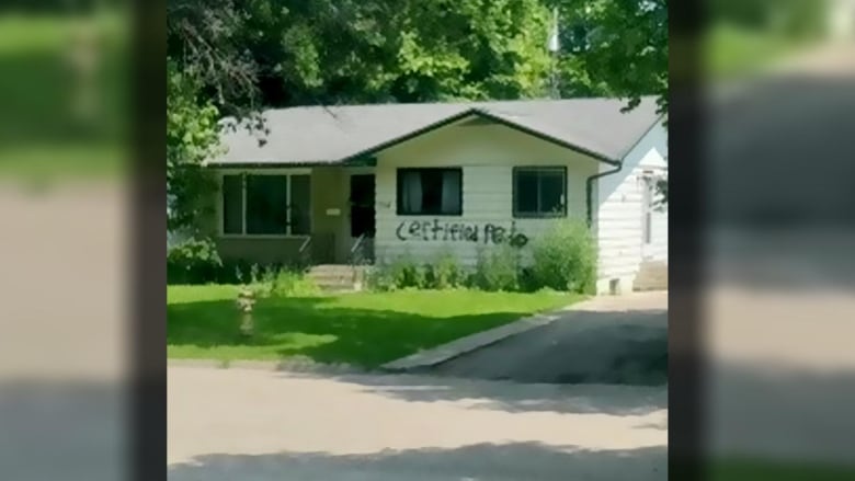 A one-storey, white house, with the words "certified pedo" spray painted across it.