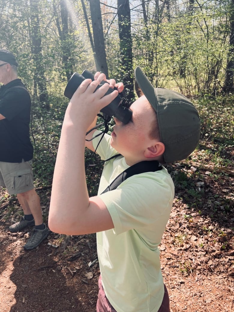 A teenage boy looking through binoculars. 