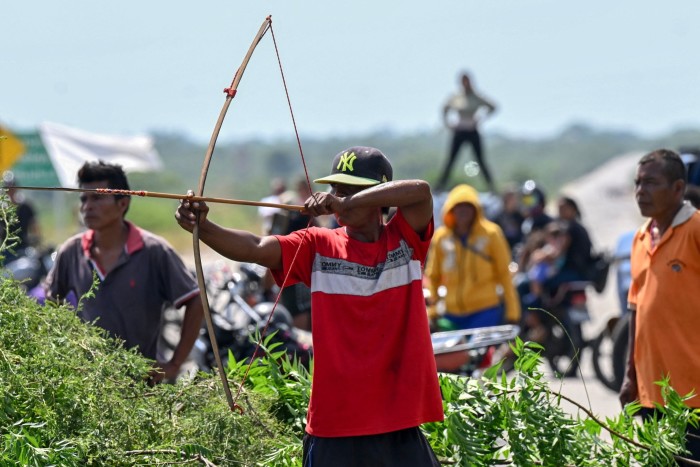 A member of the Yukpa indigenous community armed with a bow and arrow blocks the road demanding to talk to Maria Corina Machado during her road trip near Maracaibo