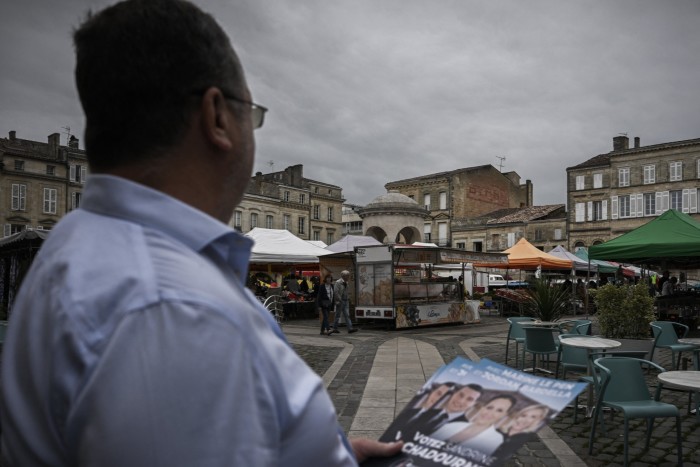 View over a man’s shoulder of the RN leaflet he is handing out in a market