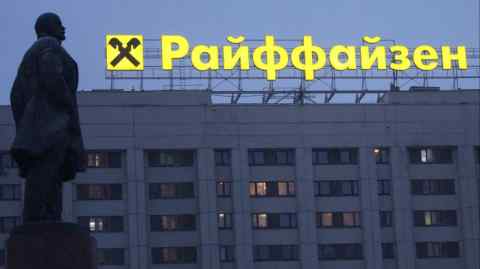 A sign advertising Raiffeisen Bank is seen behind a monument to Soviet state founder Vladimir Lenin in Moscow