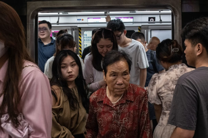 Two women, one young and the other much older, exit a crowded Beijing subway train