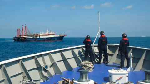 The Philippine Coast Guard patrols beside ships said to be Chinese militia vessels at Sabina Shoal in the South China Sea in April