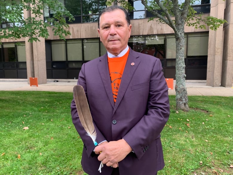 A Senator holds an eagle feather in an "orange every child matters shirt."