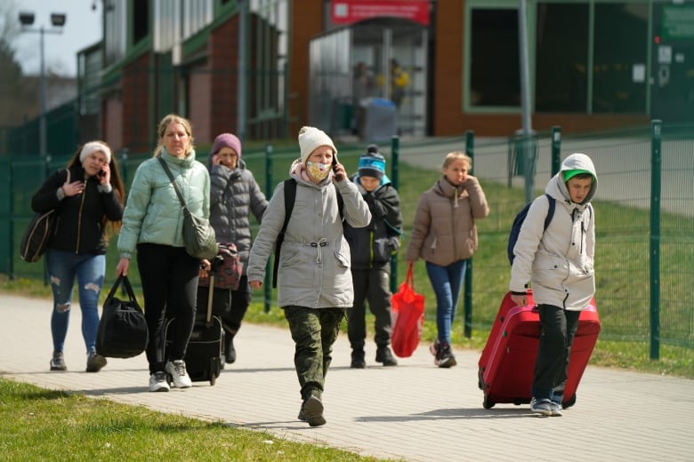 Refugees walk after fleeing the war from neighbouring Ukraine at the border crossing in Medyka, southeastern Poland