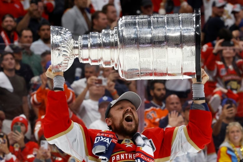 A hockey player holds up a trophy.