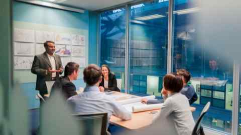 Businessman holding a meeting inside a conference room with colleagues sitting around the table