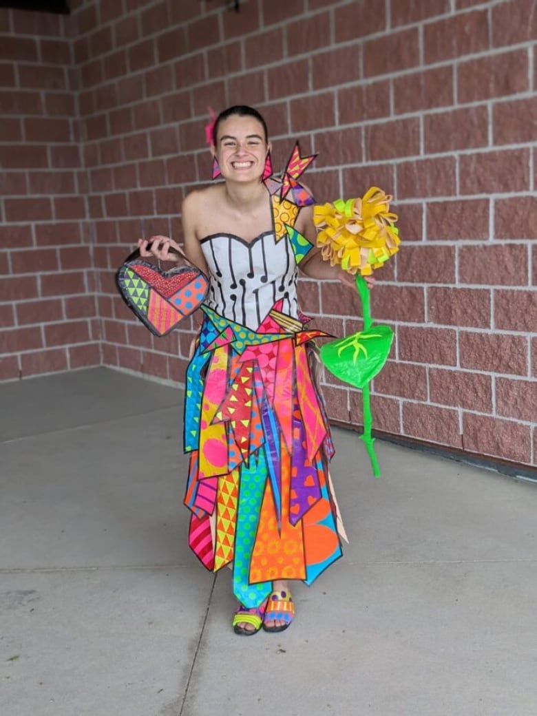 Monica Walsh poses in her duct tape prom dress, filled with vivid colours like bright blue, orange, yellow, with designs and some duct tape accessories