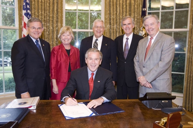 People surrounding a person singing a documents pose for a photo.