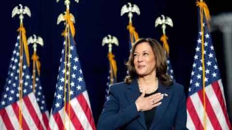 US vice-president Kamala Harris stands in front of several American flags