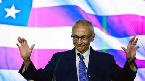 John Podesta in front of a US flag