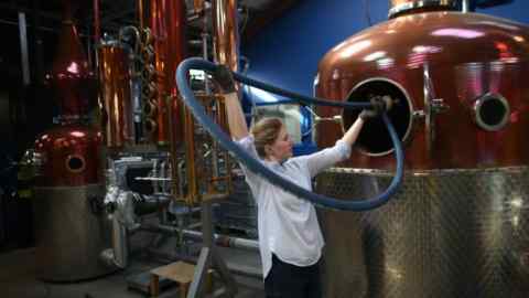 A man sticks a tube into a pot sill at a brewery