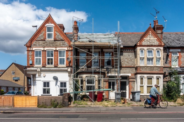 A row of terraced houses with red brick and stone exteriors. There are scaffoldings in front of it, indicating they’re under renovation