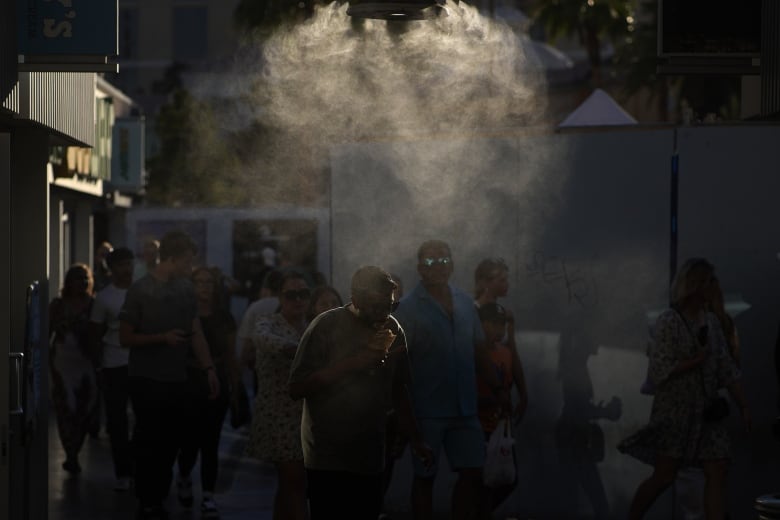 People walk through misters along the Las Vegas Strip in Las Vegas. The city set an all time record high of 48.8 C as a heat wave spread across the Western U.S. sending many residents in search of a cool haven from the dangerously high temperatures.