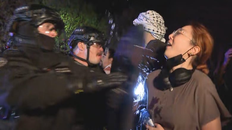 A protester interacts with police officers in riot gear.