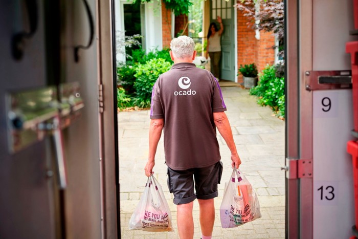 An Ocado worker delivers shopping to a customer