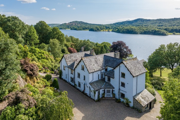 a large white-coloured house set against lake and hills