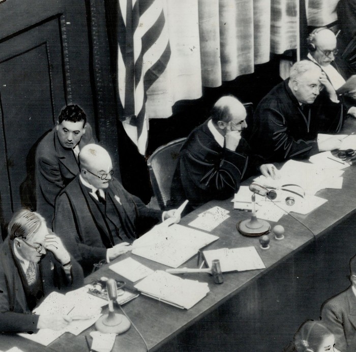 A black-and-white photograph of a row of judges seated with papers in front of them