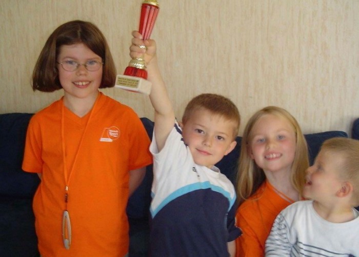 Alexis with his sisters holding a trophy, watched  by Félix, who is 3 years younger