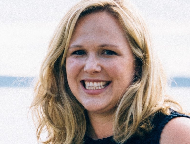 A portrait of a smiling woman with shoulder-length blonde hair.