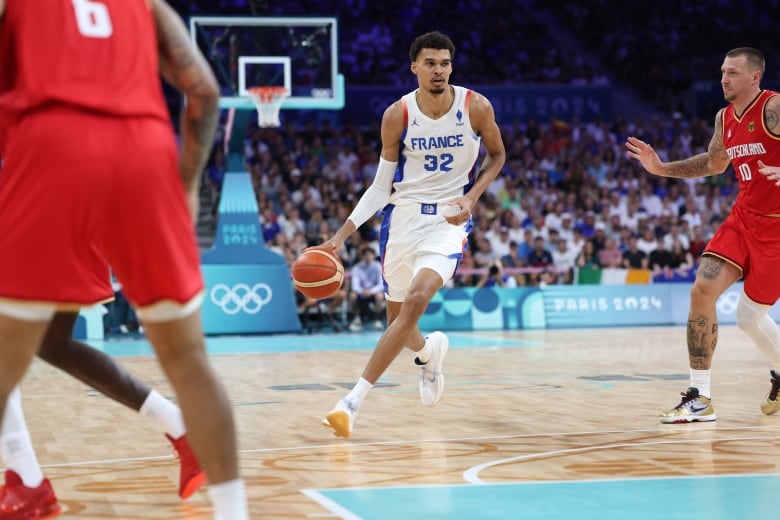 A basketball player dribbles up the floor.