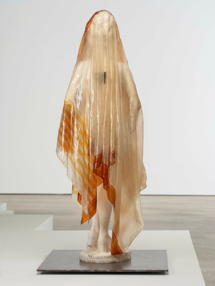 An all-white statue of a woman covered in a translucent shroud