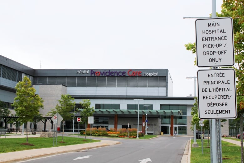 A hospital building round-about with signs indicating where to drive. There is a logo on the side of the building which reads "Providence Care Hospital." 