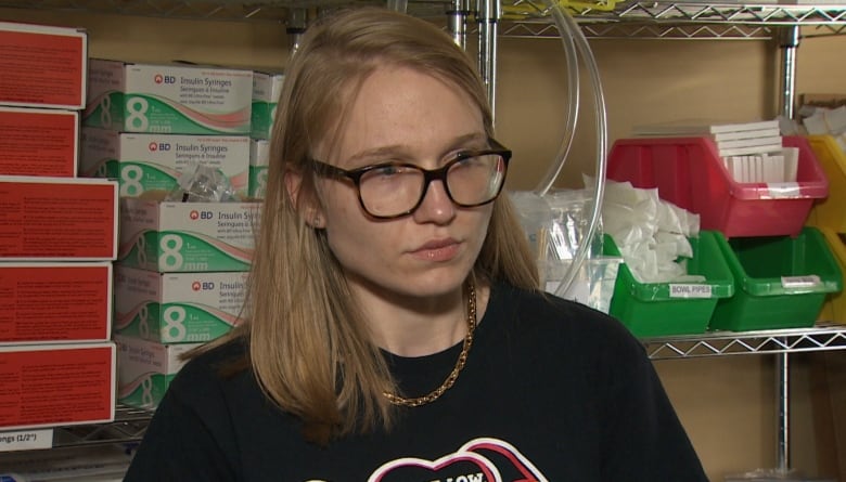 Woman stands in front of shelf filled with safe drug use supplies. 