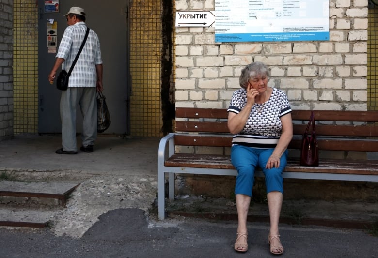 A woman sits next to the entrance to a bomb shelter in Kursk on August 16, 2024, following Ukraine's offensive into Russia's western Kursk region.