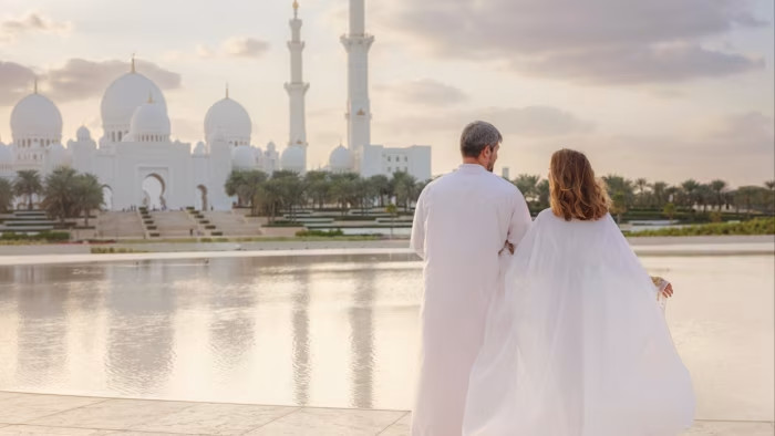 A couple visit a park with a view of Abu Dhabi’s Grand Mosque