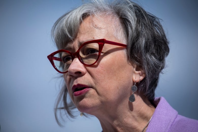 A close up shot of a woman wearing red glasses and a purple shirt. 