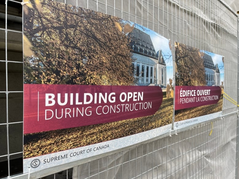 A sign is posted on a metal construction fence. It reads "Building Open During Construction" in reference to the Supreme Court's renovations.