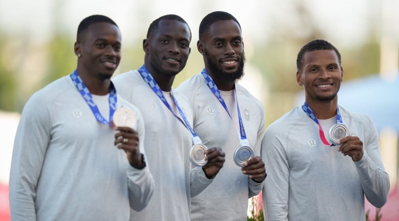 Four men's sprinters pose with silver medals.