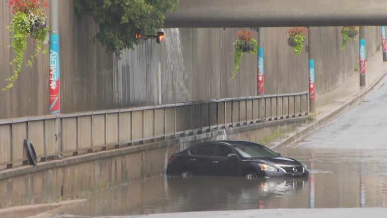 Car in floodwater under bridge 