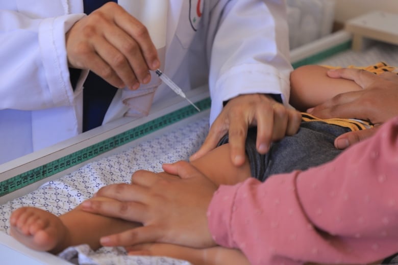 A shot is given in the thigh of a toddler