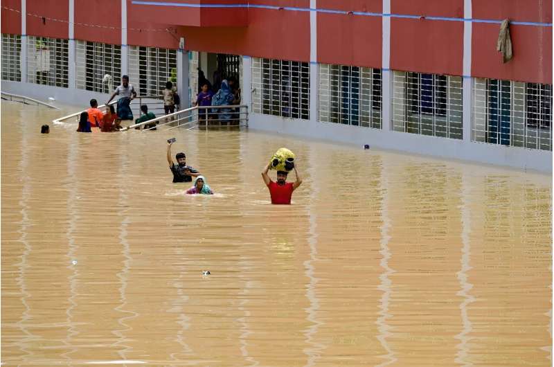 People wade through floodwaters outside a temporary shelter in Feni; more than 307,000 people are in shelters and more than 5.2 million have been affected by the floods