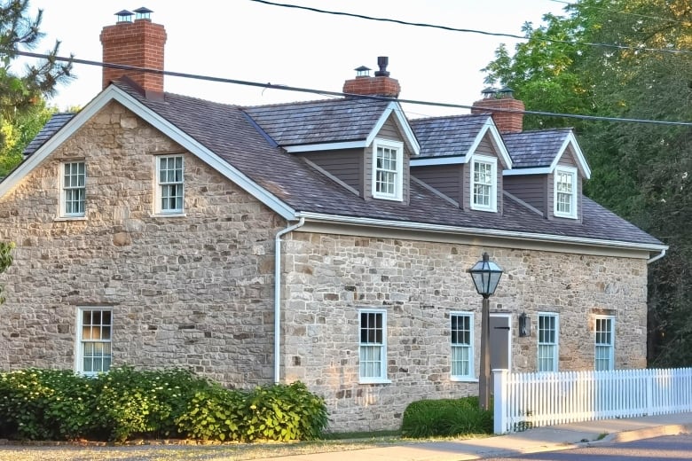 A Georgian-style stone building with three chimneys. 