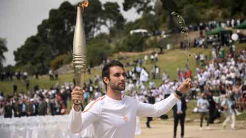 Photo of a man holding up the Olympic torch