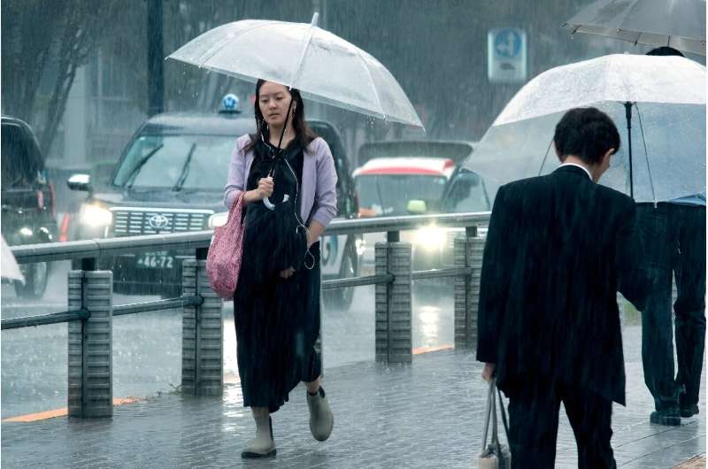 People carrying umbrellas walk across a street in Tokyo on August 30. Typhoon Shanshan weakened to a tropical storm but was still dumping heavy rains as it slowly churned through Japan