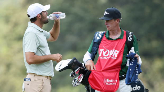 Scottie Scheffler of the United States takes a drink on the second green as his caddie Ted Scott looks on during the final round of the TOUR Championship at East Lake Golf Club on September 01, 2024 in Atlanta, Georgia. (Photo by Mike Mulholland/Getty Images)