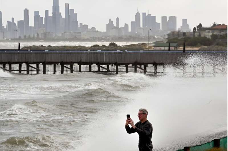 A man photographs the waves in Port Phillip Bay in Melbourne as tens of thousands of people were left without power due to wild storms battering Australia