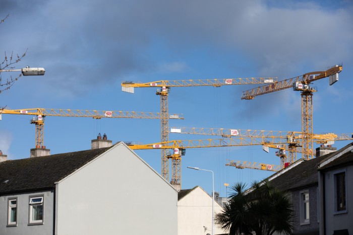 Construction cranes beyond rooftops at the Glass Bottle development site in Sandymount