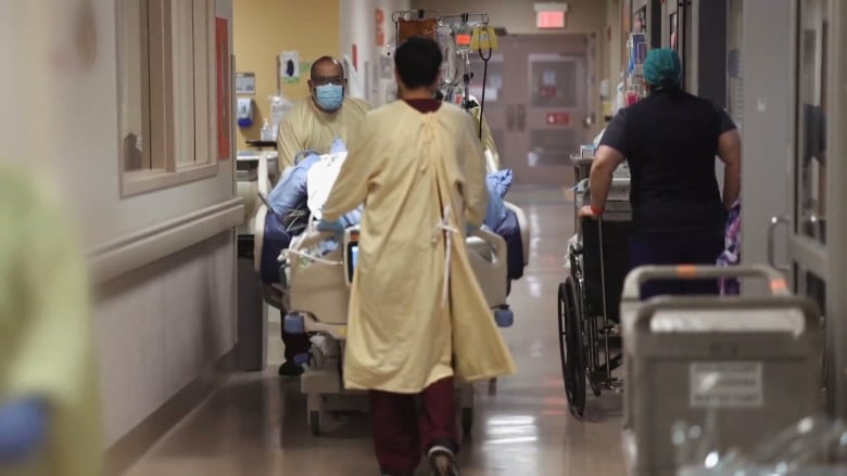 Health care workers are seen pushing a patient on a hospital bed