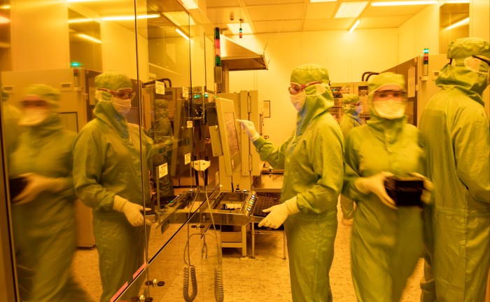 A photo of Trumpf employees working under yellow lights in the cleanroom at the company’s factory in Ulm, Germany