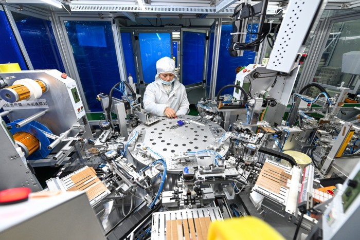 A worker places lighting components on crystal displays and modules on a production line at a semiconductor production workshop in Gao’an, Jiangxi province, China