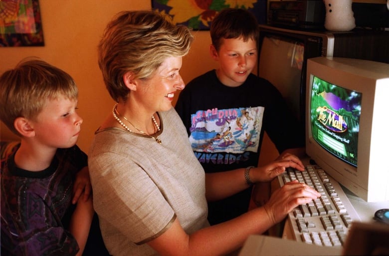 An old photo of a women using a computer while her children watch