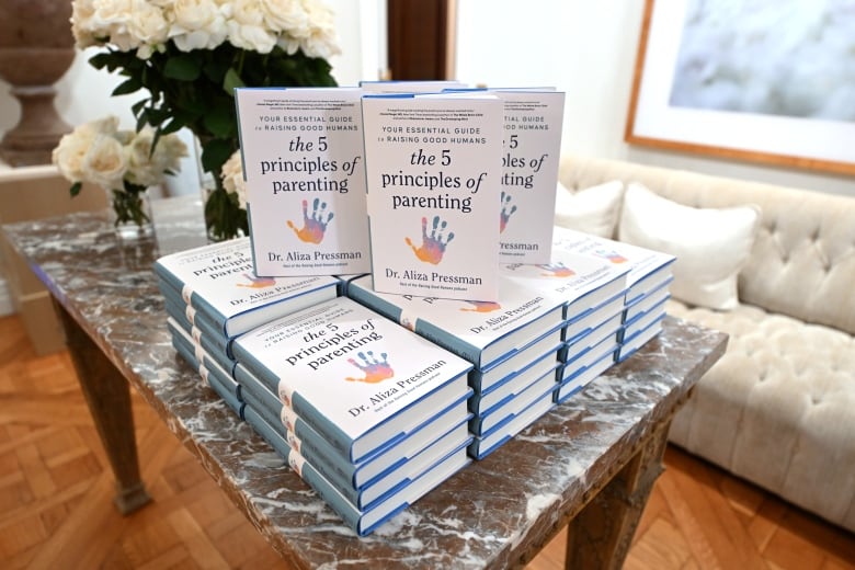 A stack of parenting books on a coffee table