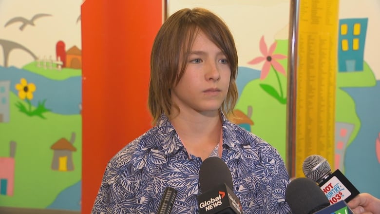 Kid standing in front of microphones. 